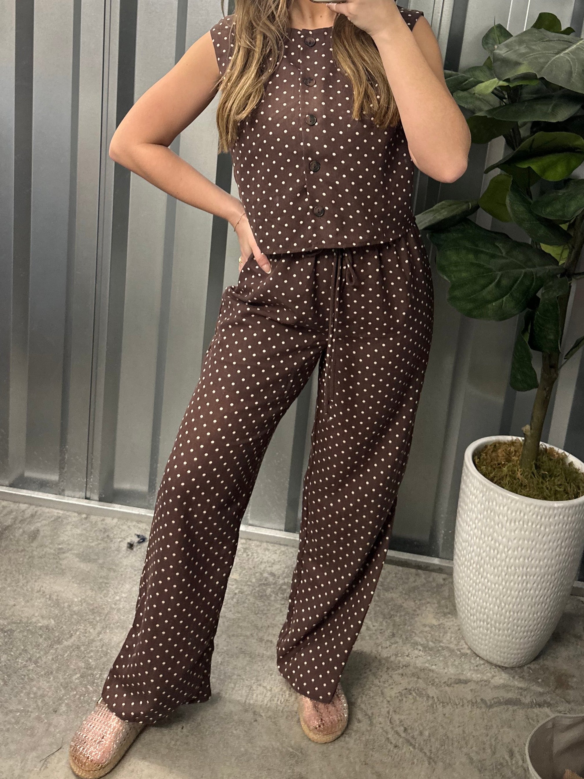 Person wearing a polka dot outfit standing in front of a metallic wall.