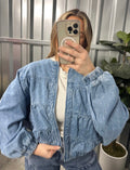 Person wearing a blue denim jacket taking a mirror selfie.