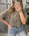 Person wearing a patterned top and jeans taking a mirror selfie.