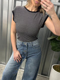 Person wearing a striped shirt and jeans standing on a staircase.