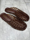 Pair of brown woven sandals on a gray tiled floor
